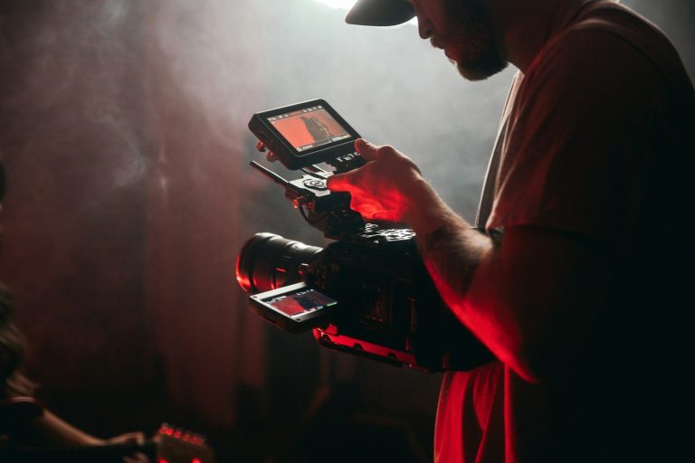 Junger Mann mit Kamera und Monitor, umgeben von rauchiger Atmosphäre.